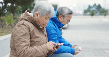 Yaşlı çift akıllı telefonlar birlikte açık Sokağı'nda kullanma 