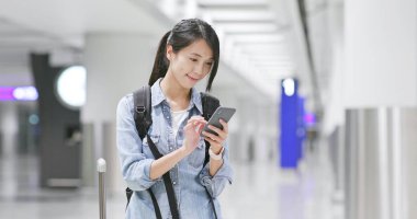 Genç kadın havaalanında cep telefonunda kontrol 