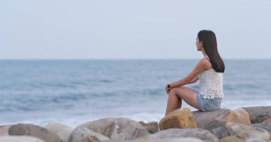 Deniz ve uzak bir görünüm oturan kadın