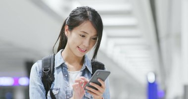 Genç kadın havaalanında cep telefonunda kontrol 