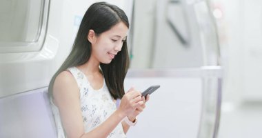 Tren bölmesi üzerinde cep telefonu kullanan kadın