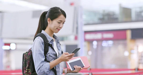 Woman checking flight number on cellphone in the airport