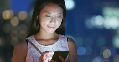 Gece akıllı telefon kullanan bir kadın.