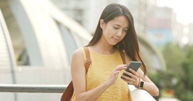 Günbatımı altında cep telefonu kullanan kadın