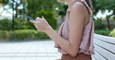 Parkta cep telefonu kullanan bir kadın.