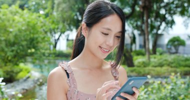 Parkta cep telefonu kullanan kadın