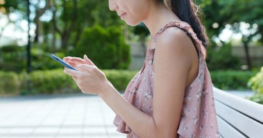 Parkta cep telefonu kullanan kadın