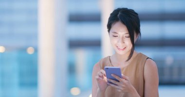 Genç kadın cep telefonuyla şehirde geceleri