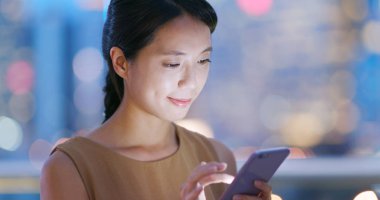 Smartphone şehirde geceleri kullanan genç kadın