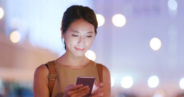 Geceleri cep telefonu kullanan bir kadın.