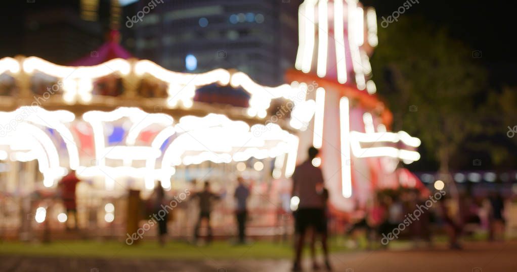 Blur view of carousel in amusement park in the evening