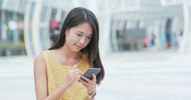 Şehirde akıllı telefon kullanan bir kadın