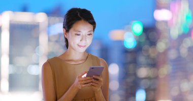 Geceleri cep telefonu kullanan bir kadın.