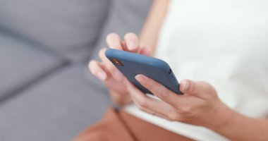 Evde akıllı telefon kullanan genç bir kadın.