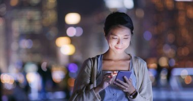 Geceleri cep telefonu kullanan bir kadın.