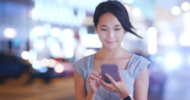 Gece şehirde akıllı telefon kullanan bir kadın.