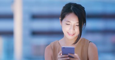 Genç kadın cep telefonuyla şehirde geceleri