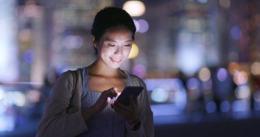 Geceleri cep telefonu kullanan bir kadın.