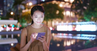 Gece şehirde akıllı telefon kullanan bir kadın.