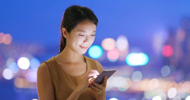 Gece şehirde akıllı telefon kullanan bir kadın.