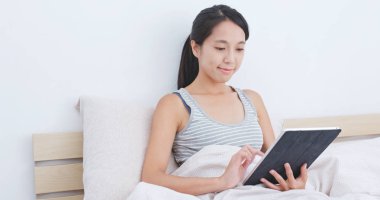 yatağın üzerine tablet bilgisayar kullanan kadın