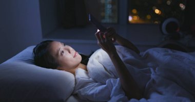 Geceleri cep telefonu kullanan bir kadın.