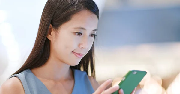 Asian young woman using mobile phone inside shopping center