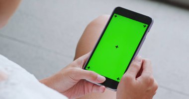 Cep telefonu ile yeşil ekran kullanan kadın