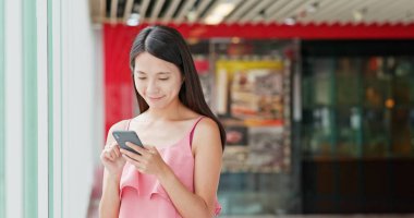 Asya alışveriş merkezi içinde cep telefonu kullanan kadın