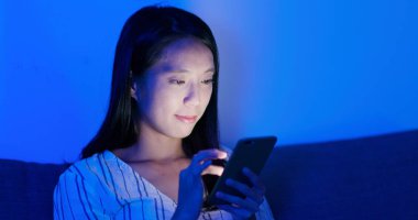 Geceleri cep telefonu kullanan bir kadın.