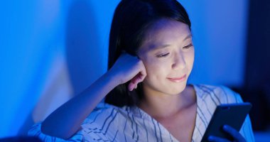 Geceleri cep telefonu kullanan bir kadın.