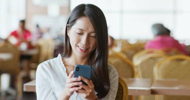 Kahve dükkanında cep telefonu kullanan kadın