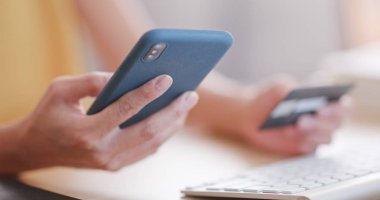 Online alışveriş için cep telefonu ve kredi kartı kullanan kadın