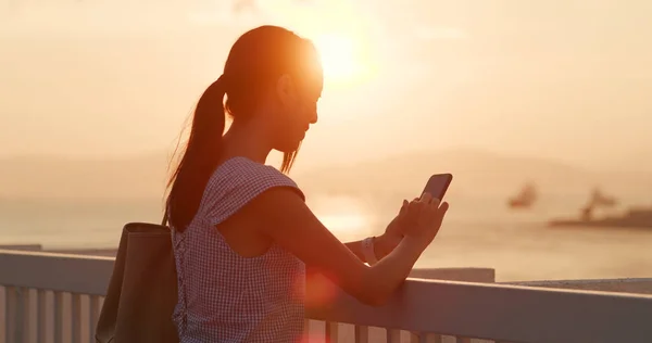 使用手机在夕阳下的女人 — 图库照片