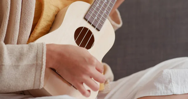 Woman play on ukulele at home