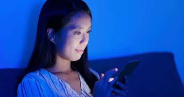 Geceleri cep telefonu kullanan bir kadın.