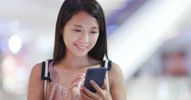 Alışveriş arka plan ile akıllı telefon kullanan kadın