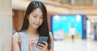 Alışveriş merkezinde cep telefonu uygulaması kullanan kadın