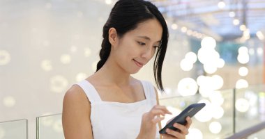 Plaza alışveriş içinde cep telefonu bakarak kadın