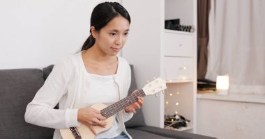 Bir şarkı üzerinde ukulele evde pratik kadın