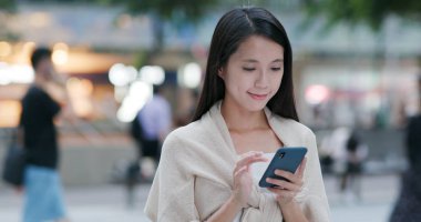 Şehirde akıllı telefon kullanan bir kadın.