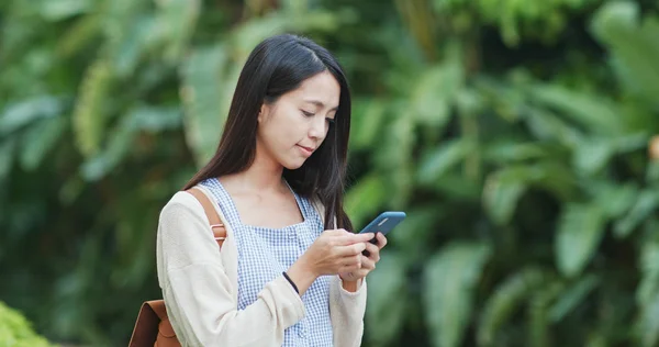 Woman using mobile phone with the background of green plant