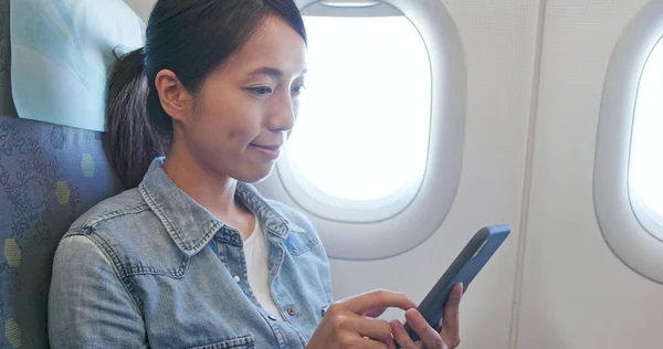 女人看着飞机上的手机 — 图库照片