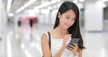 İstasyonda sms göndermek için cep telefonu kullanan kadın