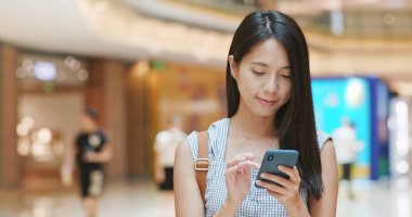 Alışveriş merkezinde cep telefonu uygulaması kullanan kadın