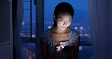 Gece akıllı telefon kullanan bir kadın.