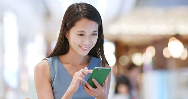 Asian young woman using mobile phone inside shopping center