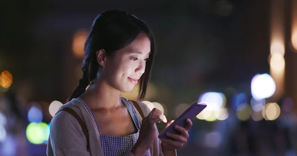 夜に街中でスマートフォンを使う女性は — ストック写真