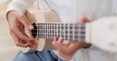 Kadın evde ukulele üzerinde bir şarkı çal