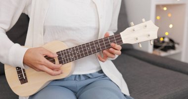 Evde ukulele üzerinde oynayan kadın